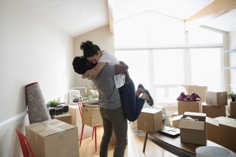 Entuzjastyczna, czuła para przytulająca się w nowym domu, rozpakowująca kartony